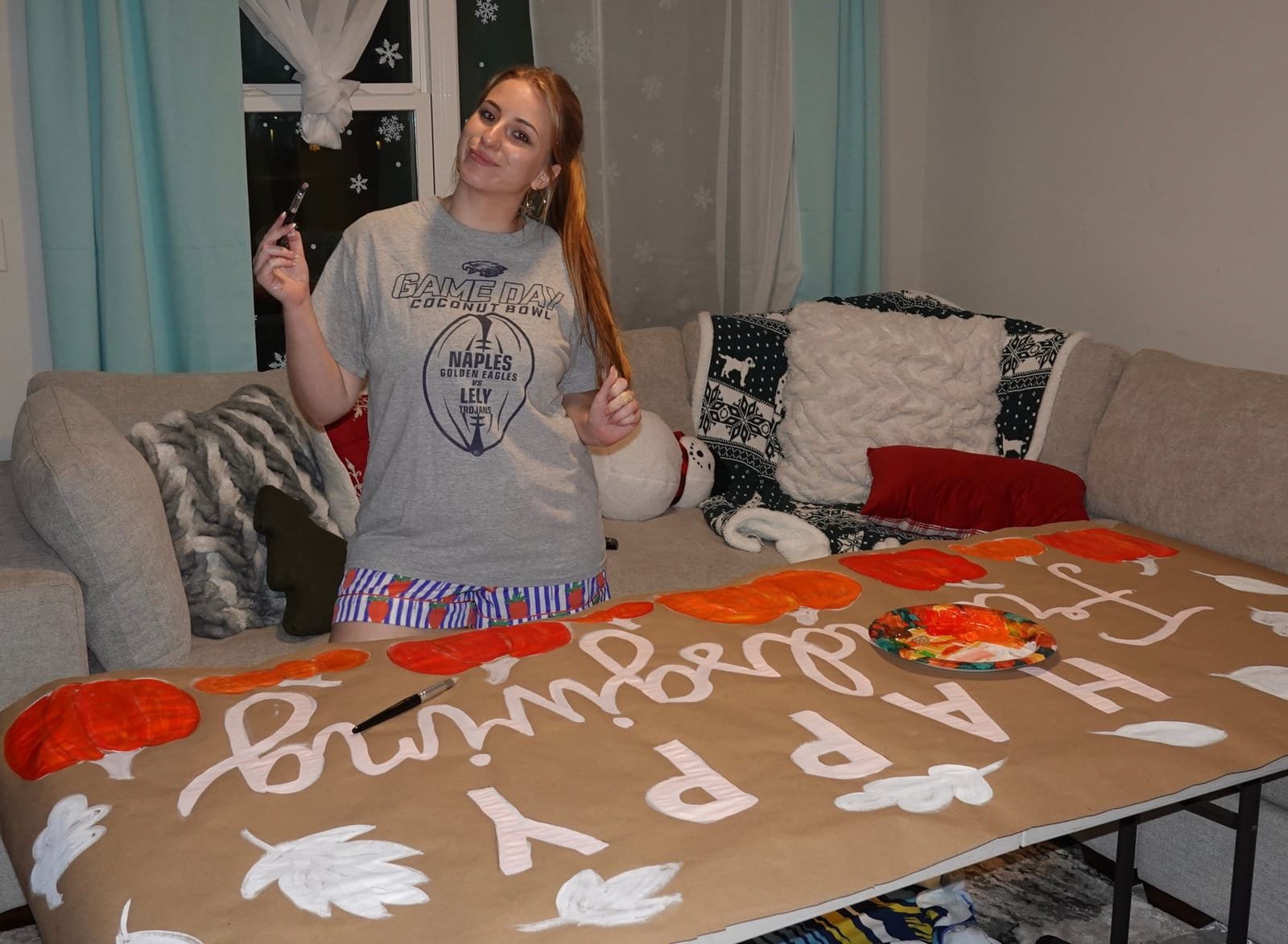 Jules painting pumpkins and lettering on a handmade Happy Thanksgiving banner