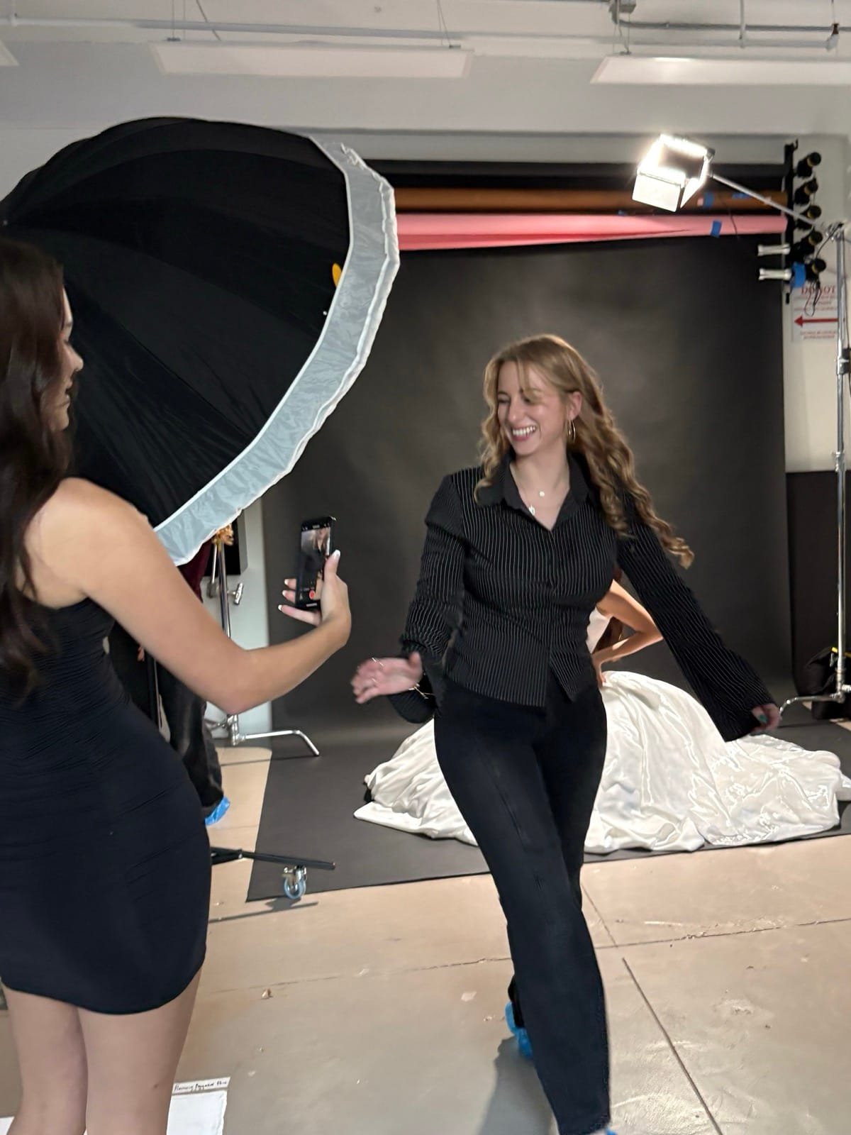 Jules in an all-black outfit laughing on a photo set between the lights and the backdrop